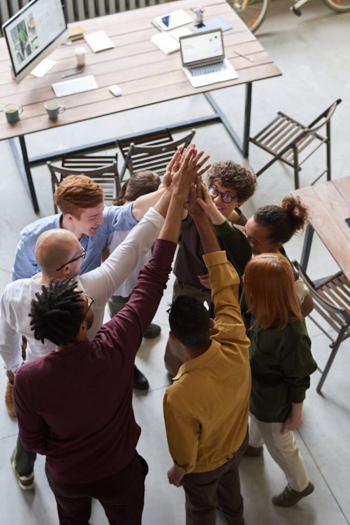 pexels photo 3184433 A diverse group of professionals high-fiving in a modern office, showcasing teamwork and collaboration.